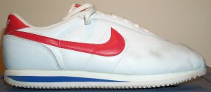 Nike Cortez shoe in white leather with a red SWOOSH and blue midsole trim